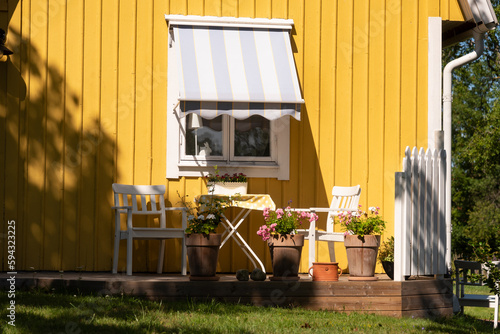 Summerly scene on the Baltic Sea island of Oeland, Sweden. Garden furniture in summer in the windbreak of a yellow Swedish house