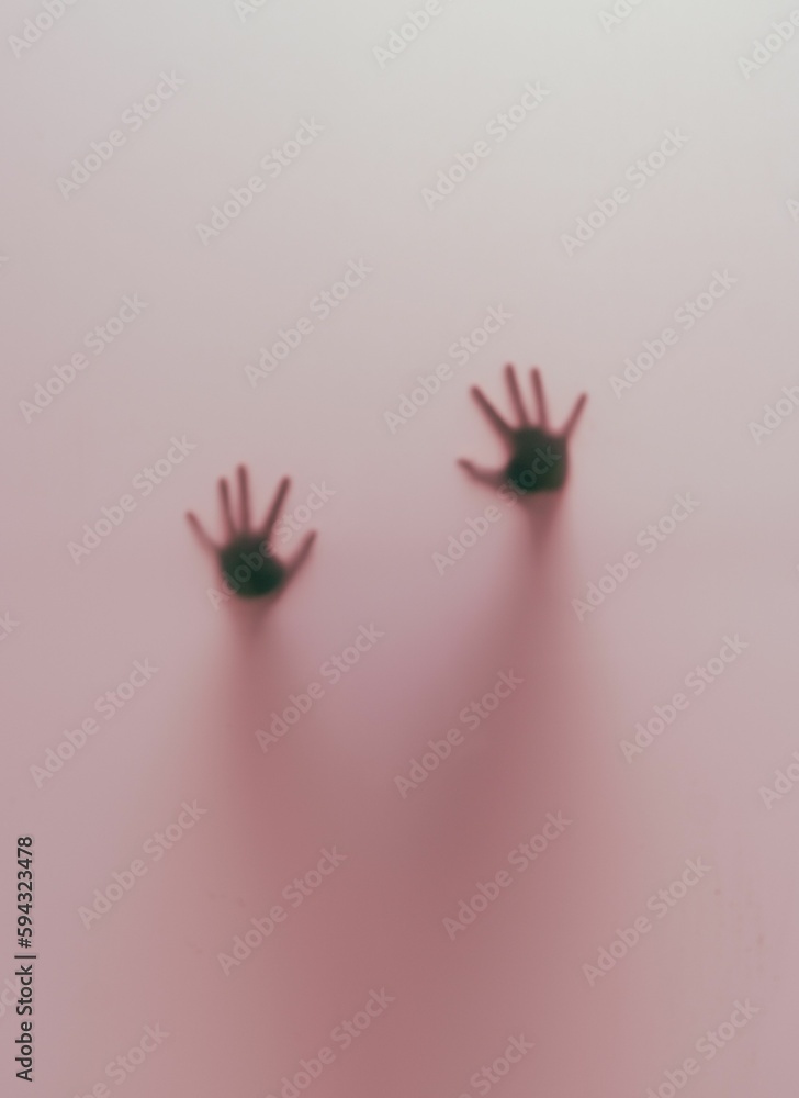 Vertical shot of blurred human hands behind a pink glass
