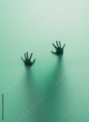 Vertical shot of blurred human hands behind a green glass