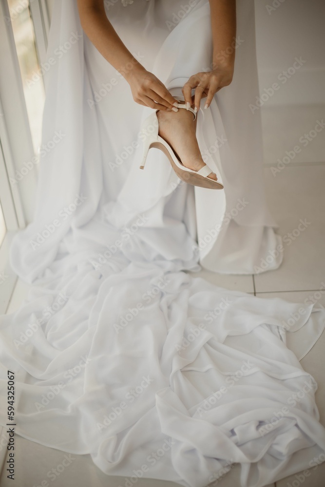 Vertical shot of the bride putting on her shoes during the wedding preparation Vertical shot of the bride putting on her shoes during the wedding preparation