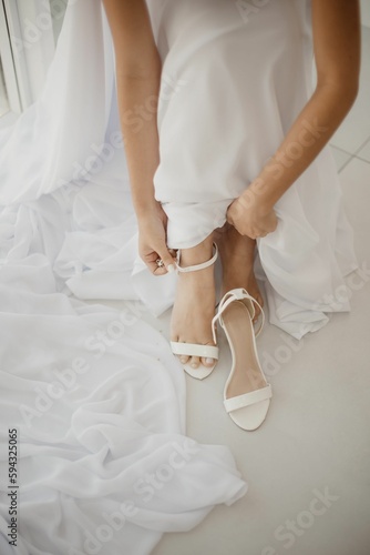 Vertical shot of the bride putting on her shoes during the wedding preparation
