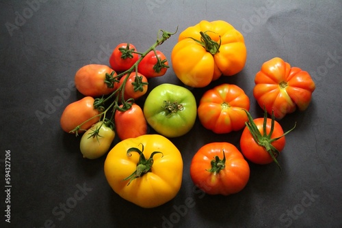 bunch with tomatoes, twig with tomatoes, various kinds of tomatoes on a dark background, scattered tomatoes, red vegetables, colorful vegetables
