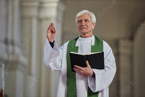 Photography Senior priest holding Bible book reading prayers and blessing believers during r