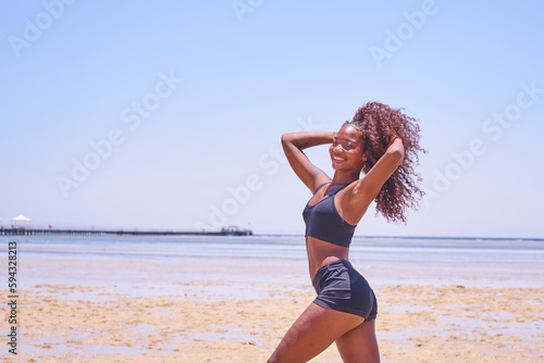 oung smiling brazilian woman on summer vacation standing at beach and enjoying sea breeze.Sexy bikini body woman feeling free on holidays. 