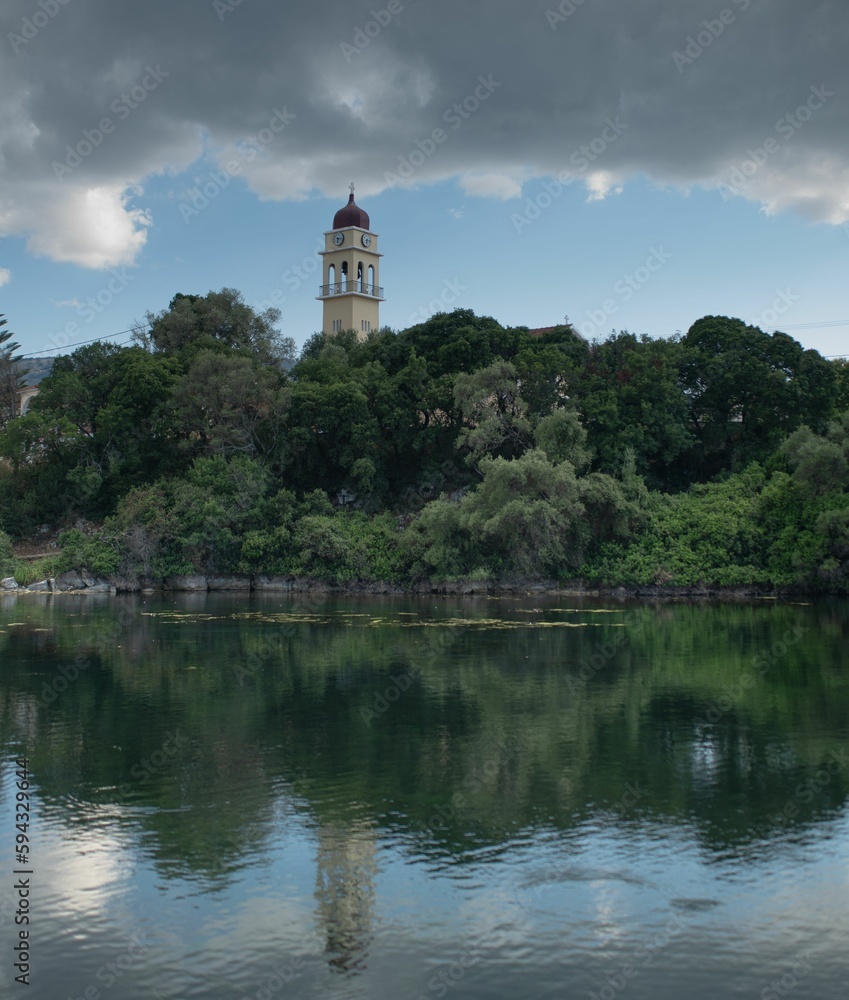 the large clock tower in the middle of a lake with many trees