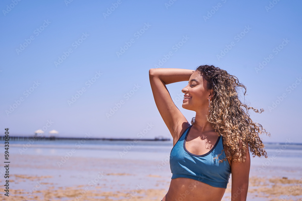 Portrait of young beautiful Brazilian girl staying on warm sunny beach and laughing.Latin woman with long curly hair enjoying her summer vacation on a sunny day.    