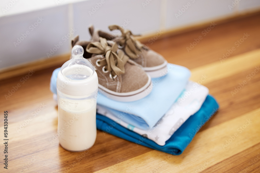 The new baby starter pack. baby clothes and a milk bottle on a table at home. The new baby starter pack. baby clothes and a milk bottle on a table at home.