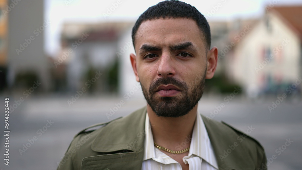 Naklejka premium Closeup face of a serious Middle Eastern man looking at camera standing in urban environment