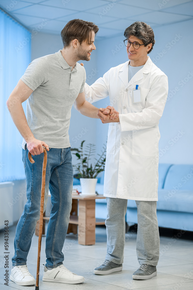 Nurse assisting a patient to walk with a stick
