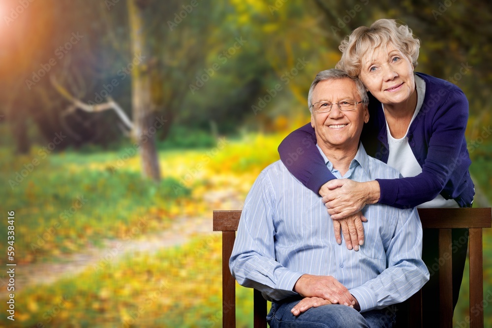 Elderly, happy couple on wooden bench in garden