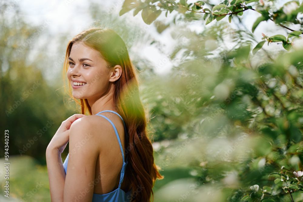 Woman smile with teeth in profile happiness in nature in the summer near a green tree in the garden of the park in a blue dress, the concept of women's health and beauty with nature sunset Woman smile with teeth in profile happiness in nature in the summer near a green tree in the garden of the park in a blue dress, the concept of women's health and beauty with nature sunset