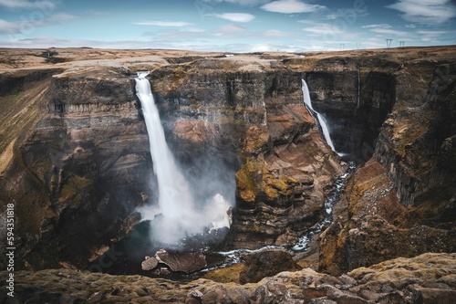 Tranquil Haifoss waterfall cascades into a deep river located in a mountainous landscape