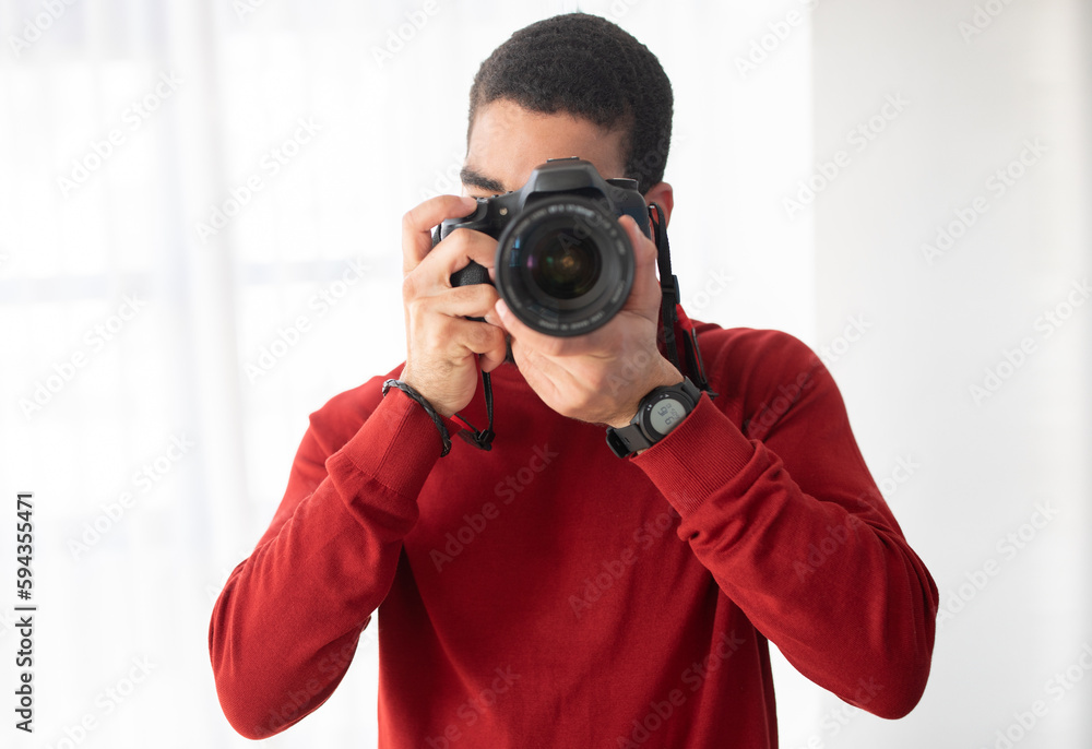 Obraz premium Male photographer taking photo with professional camera in studio