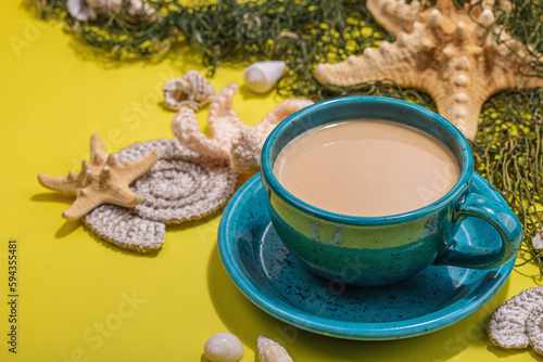 A cup of coffee in a marine style. Starfish, shells, palm leaves. Hard light, dark shadow