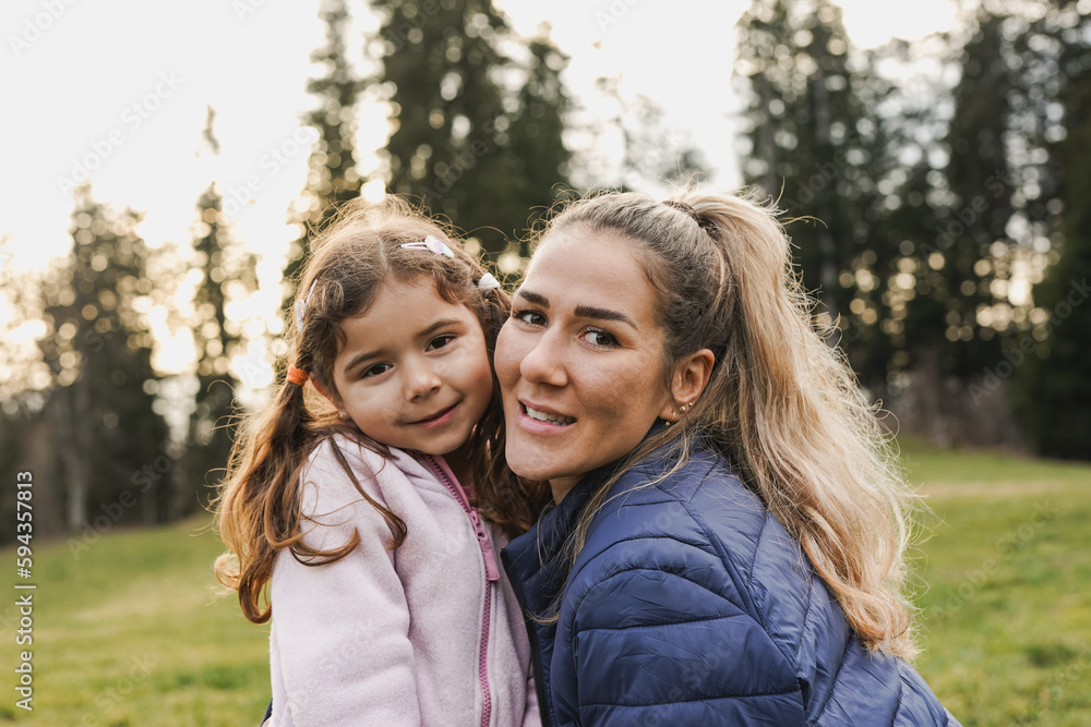 Happy mother and little daughter smiling on camera during trekking day at mountain forest - Family love - Mom day concept Happy mother and little daughter smiling on camera during trekking day at mountain forest - Family love - Mom day concept