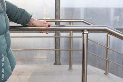 woman holding on to the railing going down the stairs. © Oleg Opryshko