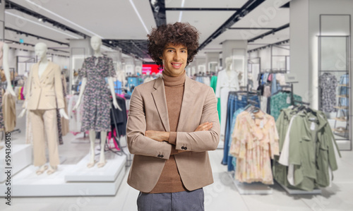 Young elegant man with a curly hair posing in front of a clothing store