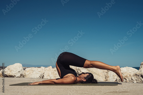 beautiful brunette girl in black overalls practice yoga against the backdrop of mountains