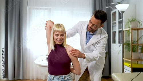 Chiropractor treating a young woman as a patient in his office.