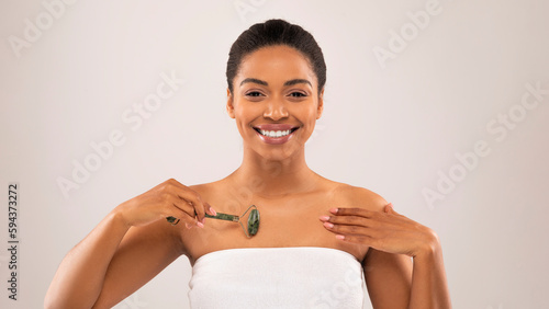 Cheery sensual black woman pampering her body after shower photo