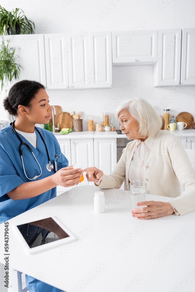 senior woman pointing with finger at pills in hands of multiracial nurse. senior woman pointing with finger at pills in hands of multiracial nurse.