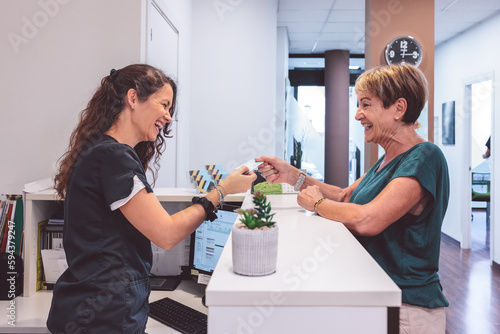 Happy client settling medical bill at reception
