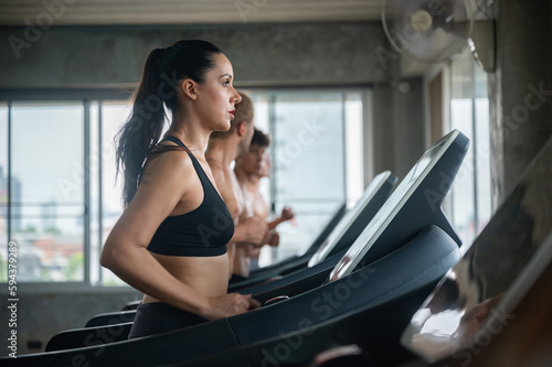 sports person female and male running and jogging in indoor fitness for health and build the body muscle on a treadmill, sports exercise person lifestyle in the gym looking strong and serious energy. © chokniti