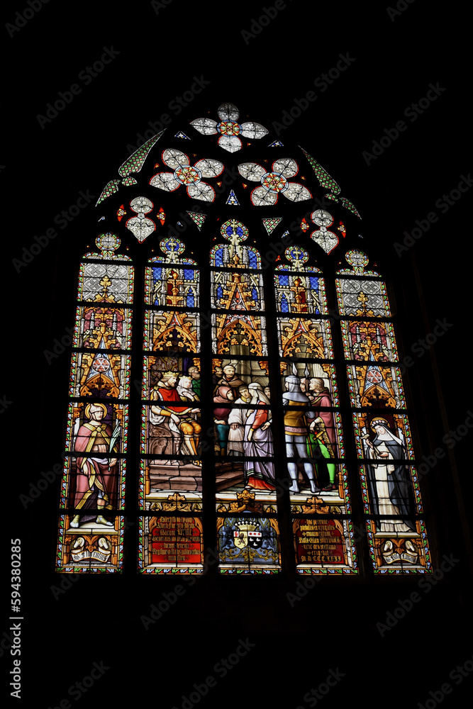 Large colorful stained glass window vitrals of cathedral church seen in low light