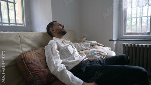 One Middle Eastern man sitting on couch unwinding after day_s work. An Arab person relaxing after burnout