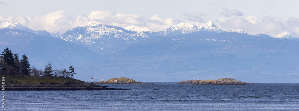 Rocky Shore in Nanaimo, Vancouver Island, British Columbia, Canada. Sunny Cloudy Day. Mountains in Background