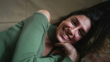 One joyful young woman smiling and laughing while laying on couch. Closeup face of adult girl in 20s feeling happiness