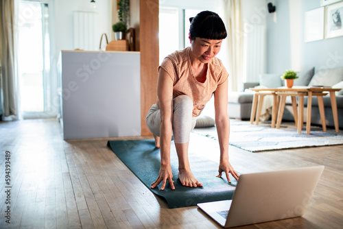 Young Japanese woman doing yoga while using a laptop