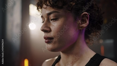 Beautiful confident Caucasian redhead sportswoman drinking water after heavy workout in smokey gym