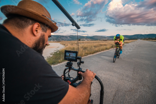 A videographer recording a triathlete riding his bike preparing for an upcoming marathon.Athlete's physical endurance and the dedication required to succeed in the sport.