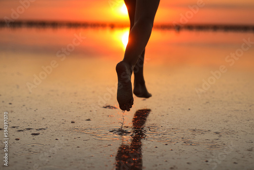 Active summer travel holiday. Cropped photo of legs silhouette of energy little child girl, boy having fun runs and plays on beach at sunset. Youth, lifestyle and happiness concept. Children's day