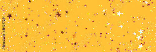 Banner with glowing golden stars and crystals confetti on a yellow background. Festive composition. Selective focus.
