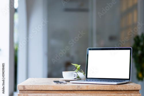 Obraz na płótnie Mockup of laptop computer with empty screen with coffee cup and smartphone on table of the coffee shop background,White screen w salonie