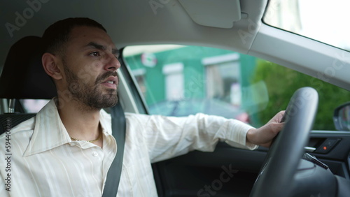 One young Arab man driving car. A Middle Eastern Moroccan male person inside vehicle holding steering wheel © Marco