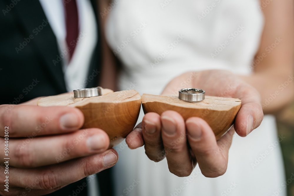 Fototapeta premium a couple holding wedding rings at their engagement ceremony in the park