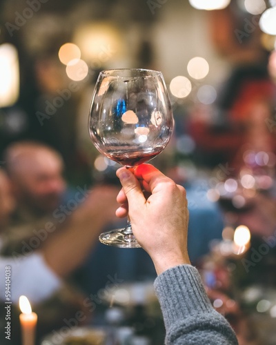 Person holding a glass of wine while sitting at a formal dinner table