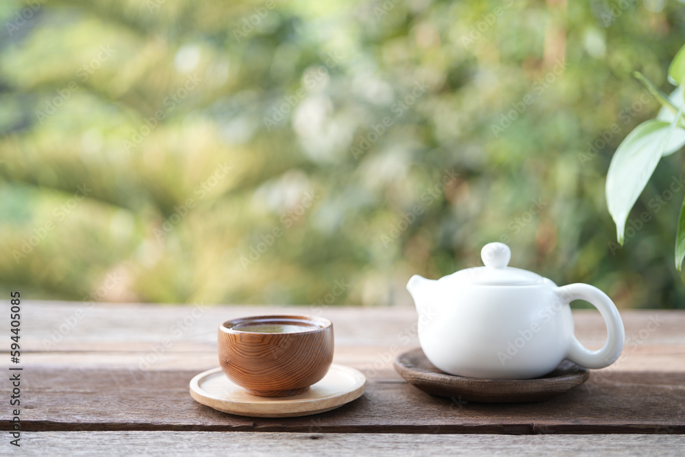 white tea cup and tea pot and on wooden tray and table balcony outdoor view with green background white tea cup and tea pot and on wooden tray and table balcony outdoor view with green background