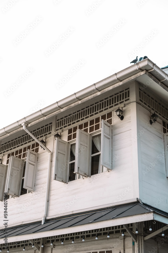 Vertical shot of a elegant white building with wooden windows Vertical shot of a elegant white building with wooden windows