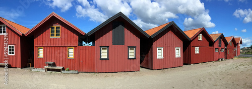 view panoramic on red traditional cabins under blus sky in sweden photo