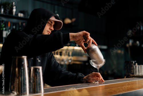 Professional bartender pours ice cubes with a scoop into a glass Process of making cold cocktails Summer fun at the bar