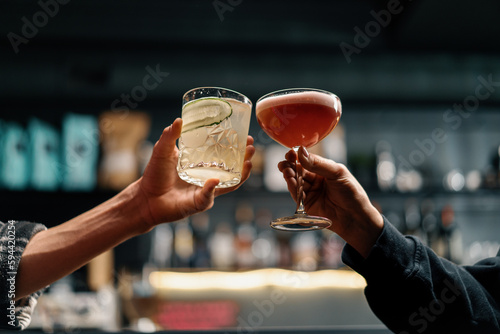 Close up of two people cheering cocktails in a bar or disco club drinks and cocktails concept