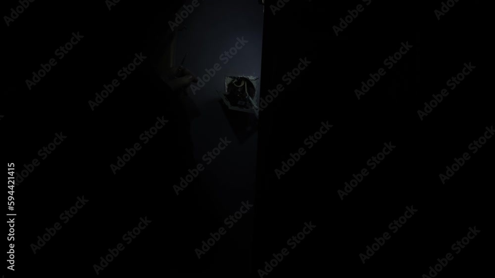 Unrecognizable electrician changing wiring in complete darkness, shining flashlight. Concept of repair by professional specialist. Unrecognizable electrician changing wiring in complete darkness, shining flashlight. Concept of repair by professional specialist.