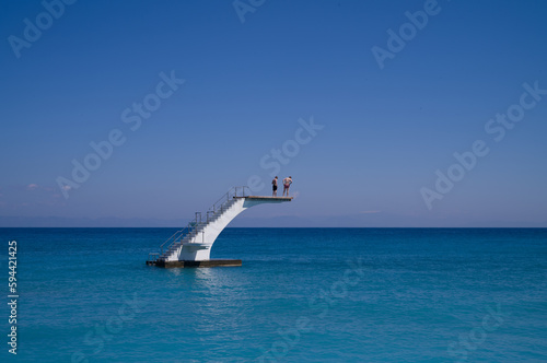 two men standing on a diving platform in the sea