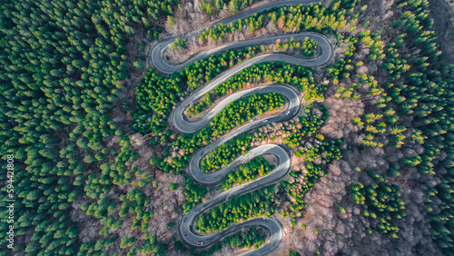 Aerial photography of a winding road in the mountains with serpentines and curves. Photography was shot from a drone at a higher altitude.