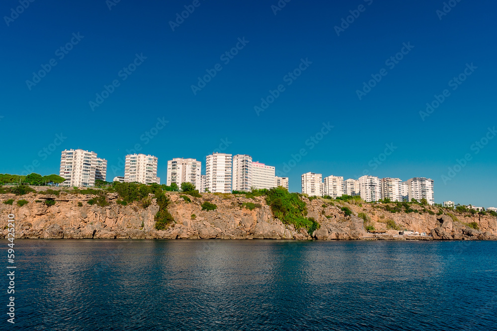 View of the rocky shore with high-rise buildings in the city of Antalya.