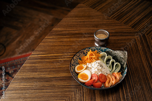 Delicious bowl of salmon with vegetables and rice covered with sauce in an oriental restaurant Healthy Asian food